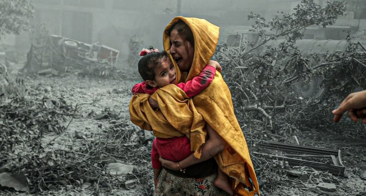 A woman holding a child flees Israeli airstrikes that hit a neighbourhood in Gaza City on 23 October 2023. Photo: Ali Jadallah/Anadolu/Getty Images